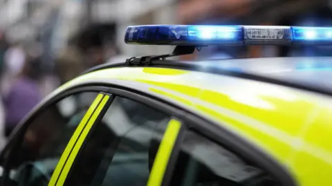 A stock image of the top of a police car, with blue lights flashing. 