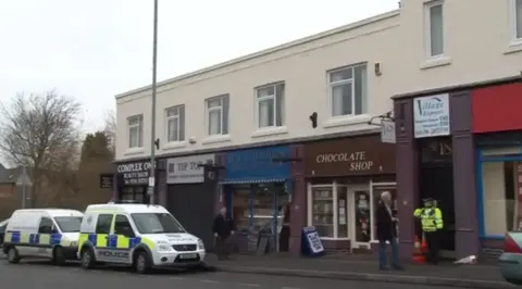 Other Two police vehicles outside a row of shops 