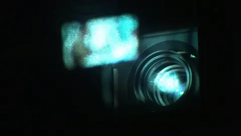 Light coming out of a film projector, with a small, blurry, rectangular image seen in front of the lens. 