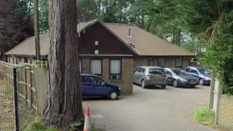 Brambletye care home, a bungalow in a wooded setting with four cars parked in the forecourt