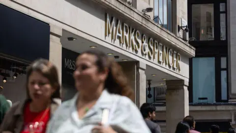 A Marks & Spencer shop on a busy high street in summer