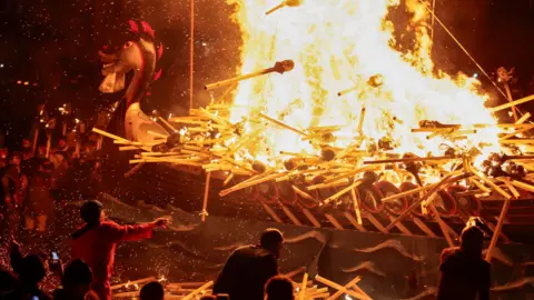 Getty Images Members of the festival throw burning torches on to the replica ship, which is ablaze.