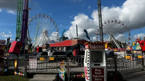 Nottingham's Goose Fair is pictured with a ride in the foreground and ferris wheels in the background