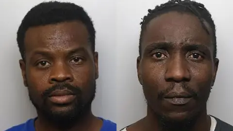 Two mugshots, side by side, showing two men. Houphouet on the left has short black hair and a goatee and beard. Sigiyo on the right has short braids and a goatee and thin beard. Both have serious expressions.