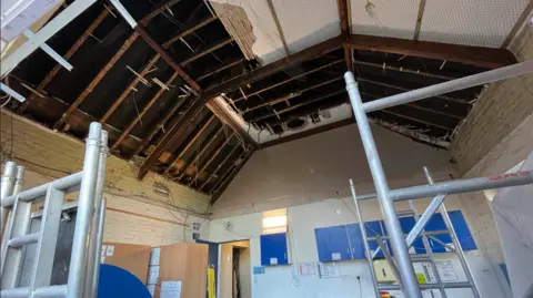 Ceiling showing damaged plasterwork and exposed beams 