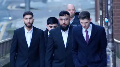 Mohammed Fahir Amaaz (left) and Muhammed Amaad (centre) arrive at Liverpool Magistrates' Court to face charges following an altercation at Manchester Airport's Terminal Two on July 23 2024. 