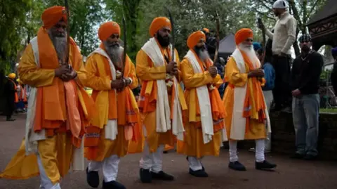 City of Wolverhampton Council A line of men in orange and white robes and orange turbans