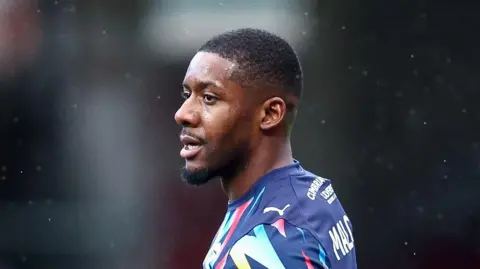 Jovan Malcolm in a Barrow away kit with his head turned to the left