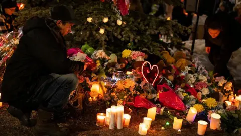 A memorial of candles and flowers are laid at a vigil for victims of a shooting at Tumbler Ridge Secondary School in British Columbia, Canada. 