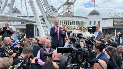 Tom Larsen-Wright/BBC Nigel Farage talking to crowds with a microphone at Clacton Pier