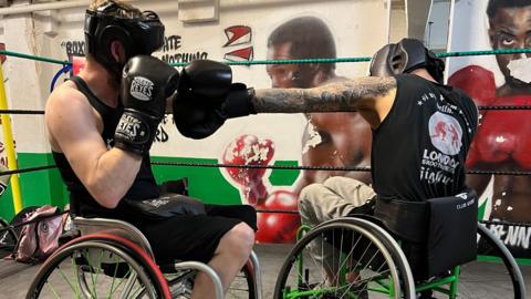 Two people in wheelchairs boxing one another