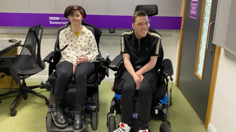 Friends Nicole Tucker and Ryley Burke, who both have cerebral palsy, pictured sitting in their wheelchairs at BBC Radio Somerset's Studios. 