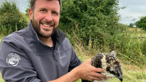 Paul Morton in a grey fleece holding an osprey