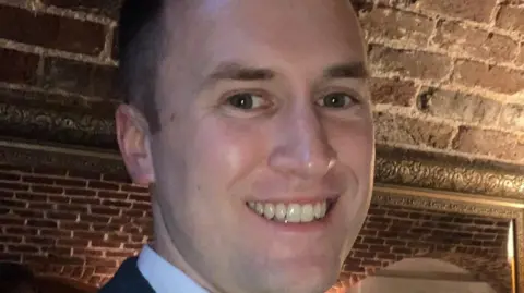 PC Ian Minett smiling at the camera, standing underneath a low, brick ceiling