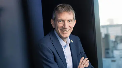 David Wright David Wright, smiling with his arms crossed. He has short grey hair, is wearing a blue blazer and pale blue/white shirt with the collar open.