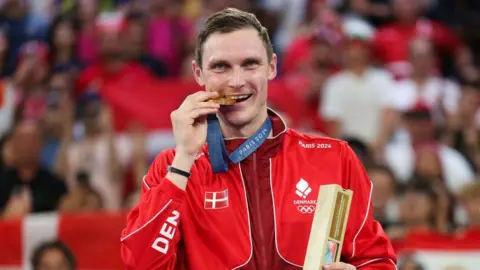 Viktor Axelsen bites his Olympic gold medal