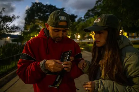 Fritz Pinnow Fabriccio Díaz and Lucía Ramírez are loading film into a camera that was made in the 1930s, which they were allowed to borrow from a camera store and try out.