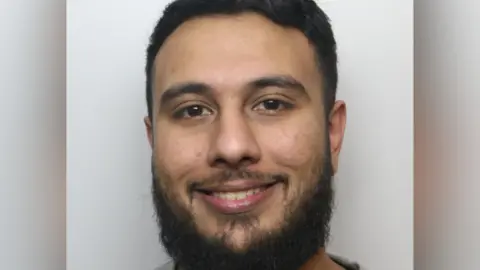 West Yorkshire Police Police custody image of a man with a beard smiling.