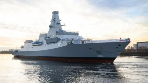 MOD/Crown Copyright A light grey warship on a river