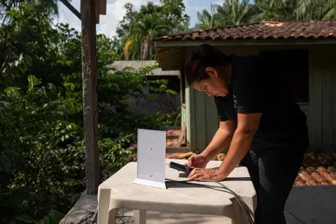 Getty Images A worker sets up a Starlink router to provide satellite internet service to a chocolate store on Combu Island in Belem, Para state, Brazil