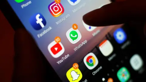 PA/ Yui Mok A close-up of a mobile phone with icons of various social media platforms.