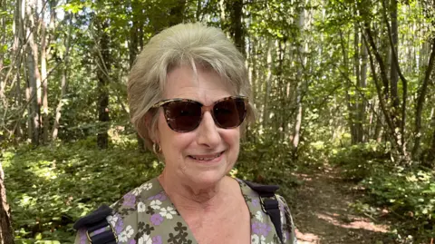 Julie Brown from Barming standing next to coppiced trees in Oaken Wood, Barming