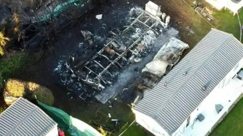 Other caravans surround the burnt out remains