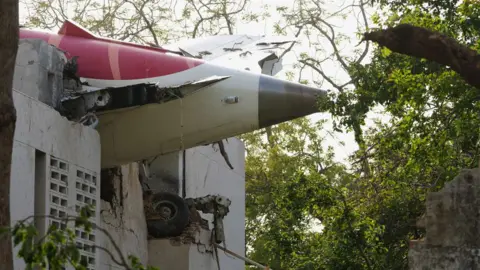 Wreckage of the tail section of the Air India aircraft sticks out of a building at the crash site