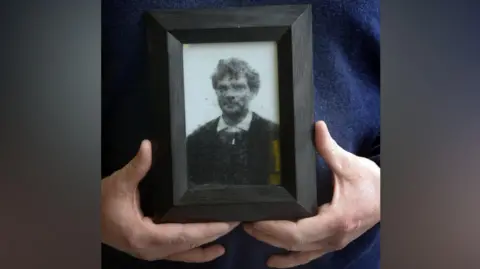 Hands holding a framed picture of John Patrick Cunningham.