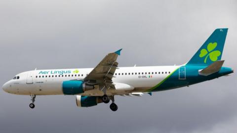 An Aer Lingus flight flying in a grey sky 