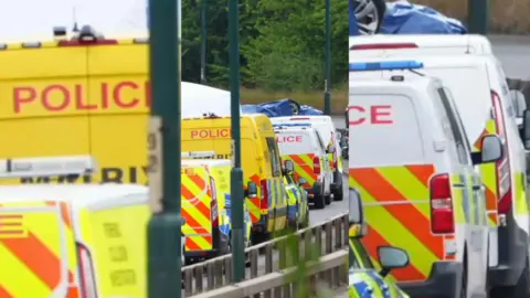 A row of police vans on a dual carriageway.
