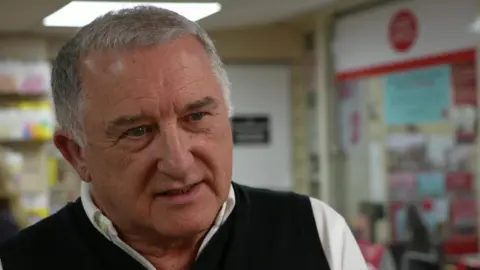 Jerry Brown, a sub-postmaster who has been running his branch in Hadleigh, Suffolk, wearing a dark jumper and a white shirt