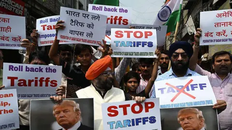 Bloomberg via Getty Images Demonstrators hold signs saying stop tariffs and roll back the tariffs, with Donald Trump's picture, during a protest against US President Donald Trump's 50% tariffs on India, in New Delhi India, on Saturday, Aug. 30, 2025