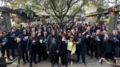Stephen Rea A large crowd of people with most dressed as Ozzy Osbourne. Those dressed as Ozzy Osbourne are wearing black jackets, black trousers, wigs and T-shirts with Ozzy Osbourne's face on. 