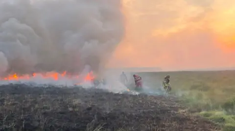 Hay-on-Wye Fire Station Firefighters tackle flames from grass fire that has sent clouds of smoke into the air