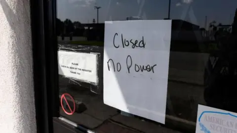 Reuters Sign on glass door of business that reads "Closed No Power" 
