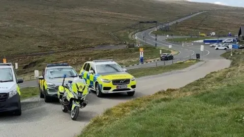 Police cars and a motorbike parked ahead of the Bungalow section of the Mountain Road