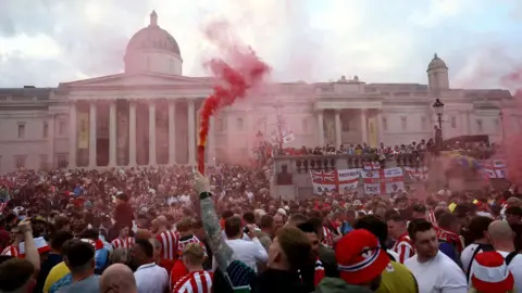 Sunderland AFC fans, many wearing red and white striped kit, congregate in Trafalgar Square 