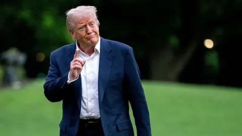 US President Donald Trump holds his right hand up in a gesture