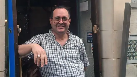 James Fitzgerald / BBC Riad stands at the door of his restaurant