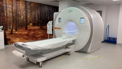 BBC An image of a CT scanner in a hospital room