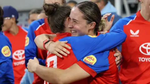 Alice Capsey is hugged by a team-mate
