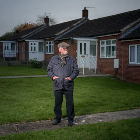 Simon Hill HonFRPS Former miner Walter Sherriff standing in front of a row of houses