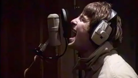Liam Gallagher sings into a microphone in Rockfield Studios in 1995