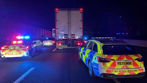 Two police cars pull over a lorry on a motorway 