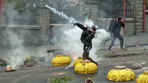 AFP/Getty Images A young man throws a tear gas grenade as other protesters run behind him on a street in Antananarivo.