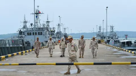 Getty Images Военнослужащие камбоджийских военно-морских сил идут по причалу военно-морской базы Реам, на фоне кораблей ВМС