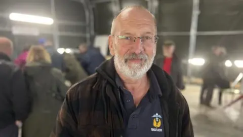 Mike Scarrott with a short grey beard and glasses smiling into the camera