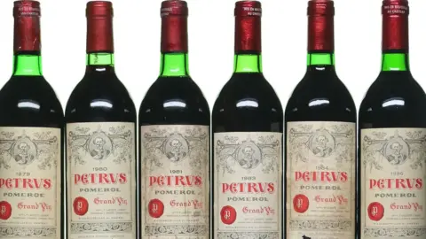 Green bottles of wine with red wax-sealed tops and the branding "Petrus"