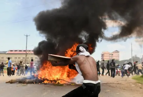 Demonstrator stands in front of burning tyre in Nanyuki, Kenya